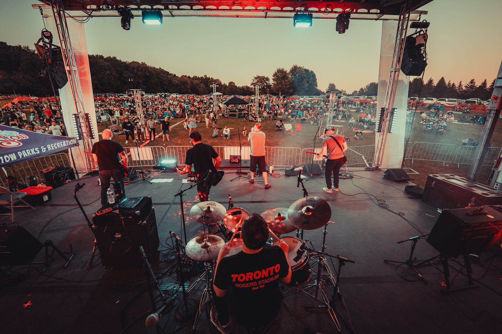 View from behind the drum kit over a huge festival crowd at sunset